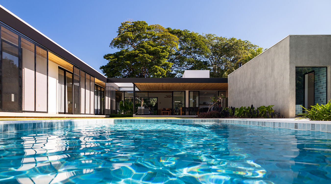 vista dos fundos da casa com destaque para a piscina e beiral em estrutura metálica com forro de madeira