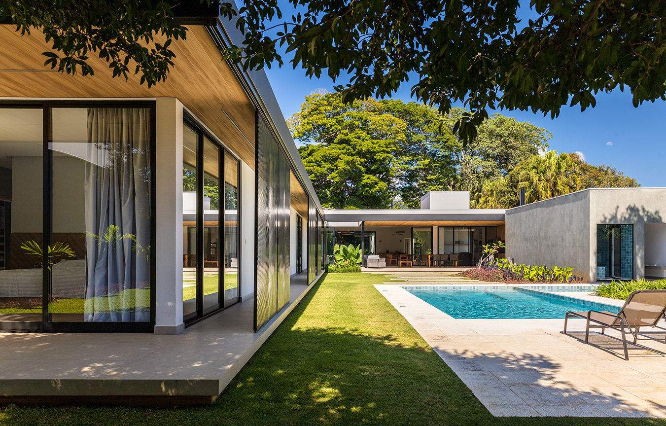 vista dos fundos da casa com destaque para paisagismo, piscina e beiral em estrutura metálica com forro de madeira